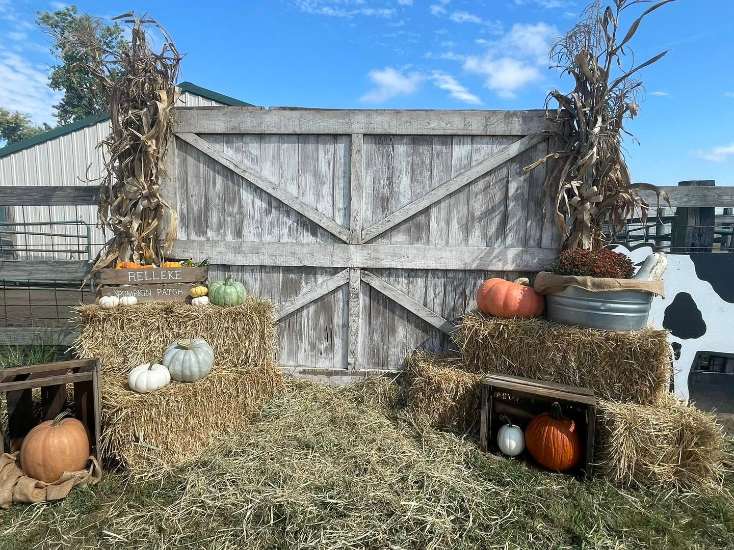 A rustic barn-door photo spot with hay bales and pumpkins